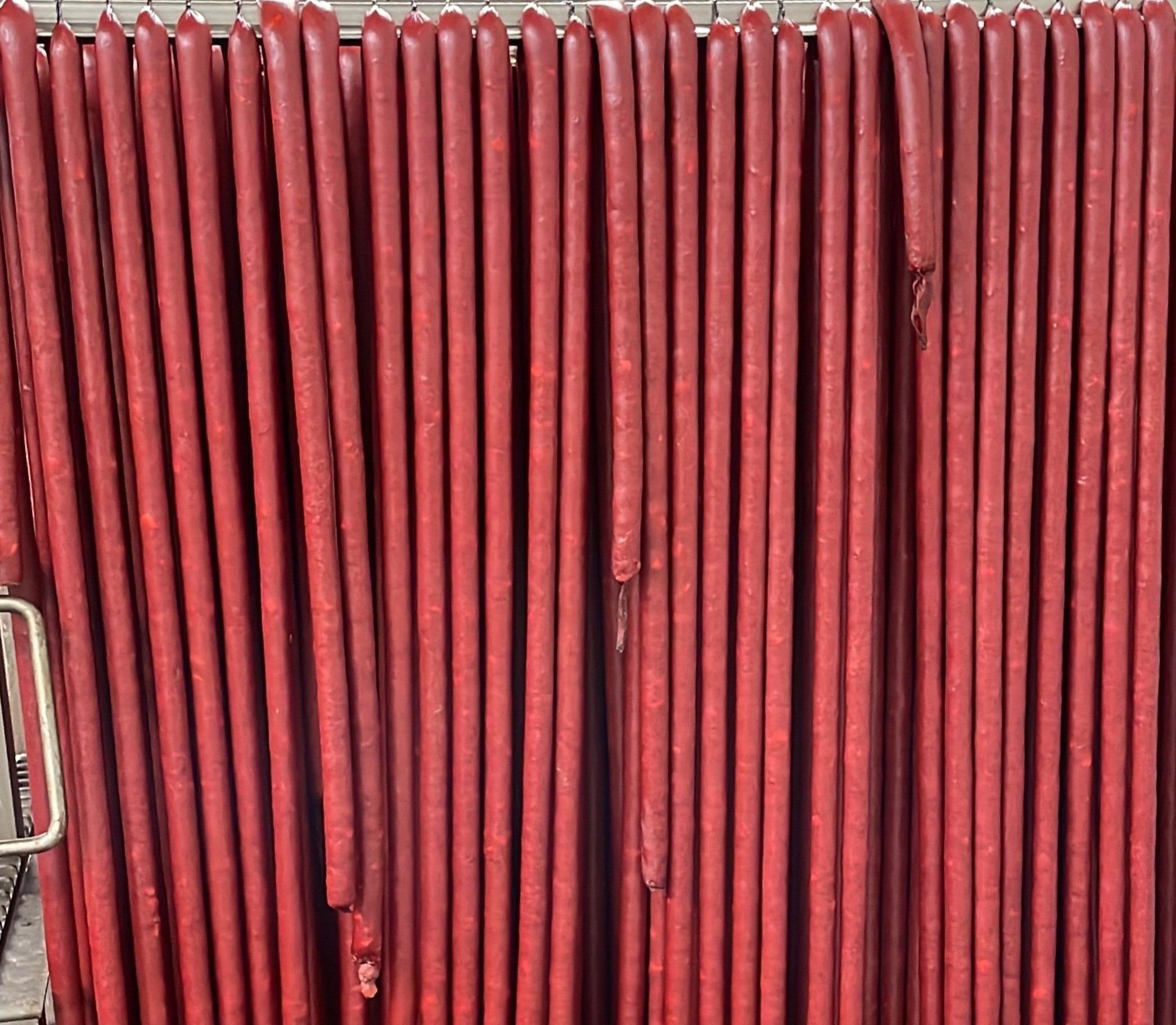 05902B4D-7186-4351-B490-29E23A6AA47B A close-up image of multiple red hot dog sausages neatly arranged in a row, showcasing their smooth texture and vibrant color.